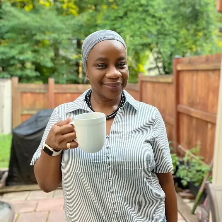 Beautiful image of Musu holding a coffee cup standing in her backyard garden
