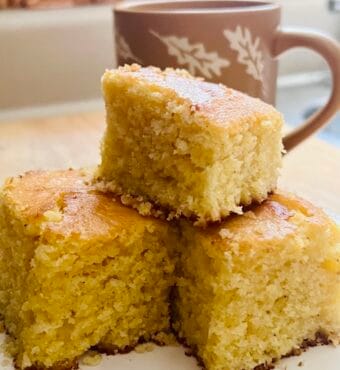 3 golden corn bread pieces with a mug in the background